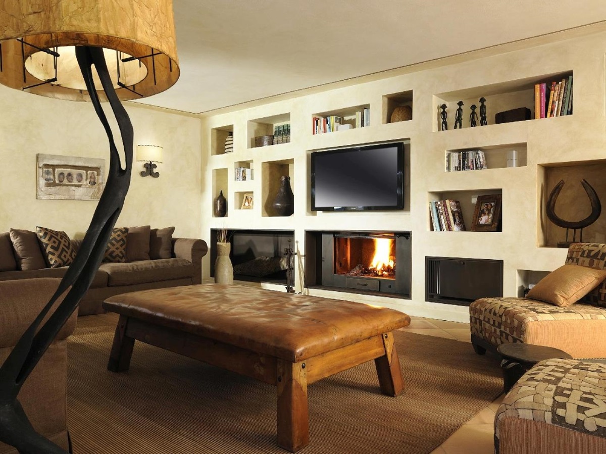 Living room with lamp, bookshelves, TV, sofas, armchairs and fireplace at La Feniglia in Porto Ercole, Tuscany