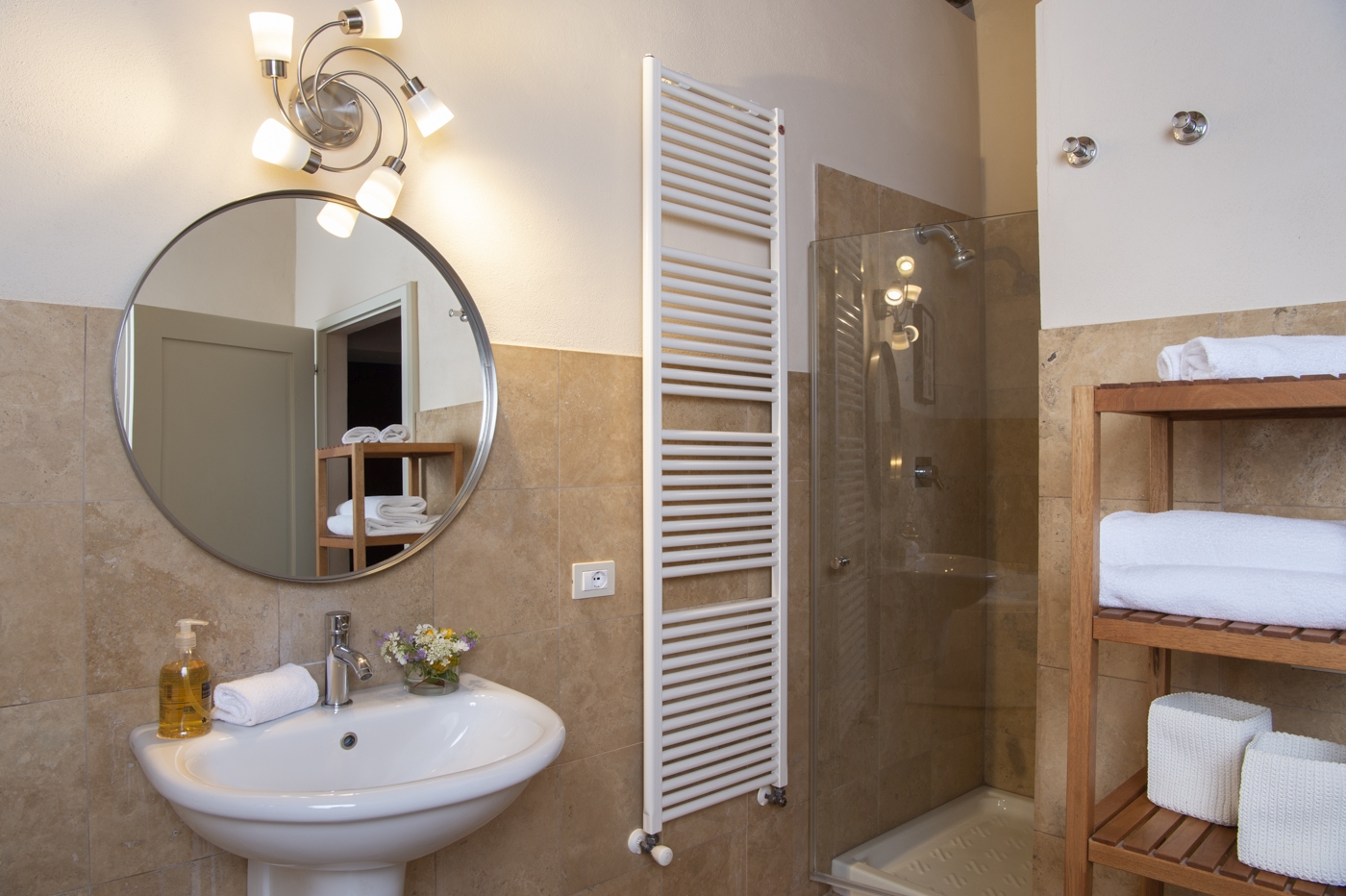 Bathroom with sink, mirror, towel rail, shelves and shower at La Gavelli in Tuscany, Italy