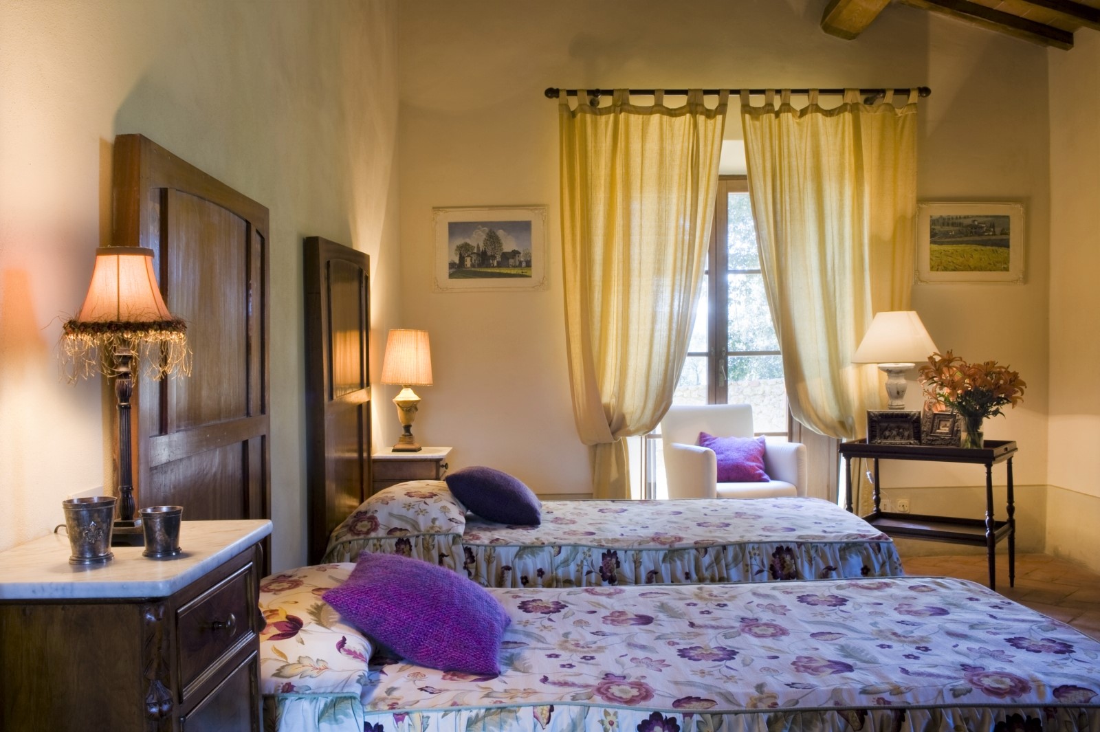Twin room with twin beds, bedside tables, lamps, flowers and armchair at La Gavelli in Tuscany, Italy