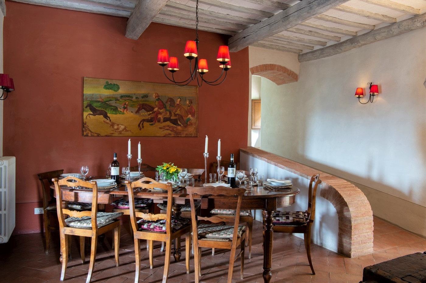 Dining area with dining table, chairs, candles, flowers, painting and hanging light at La Gavelli in Tuscany, Italy