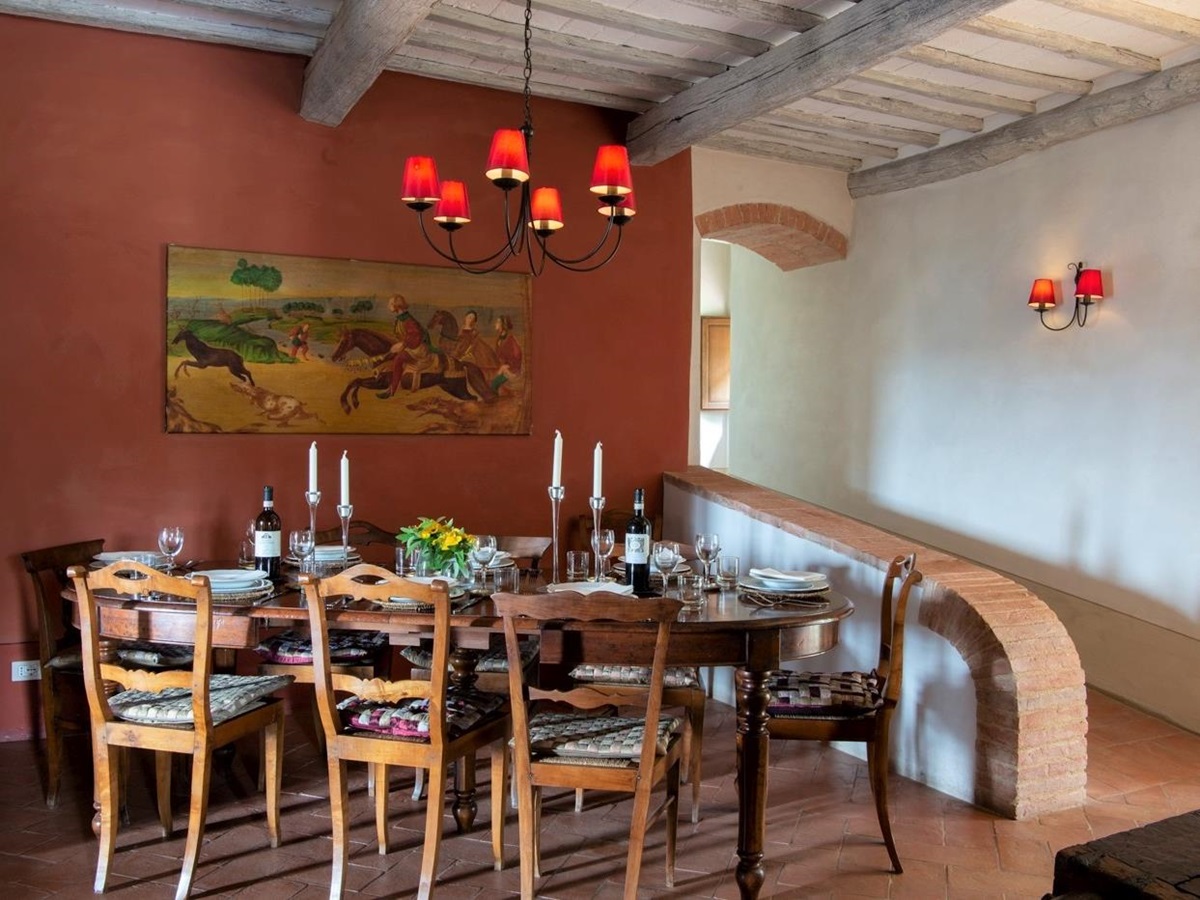 Dining area with dining table, chairs, candles, flowers, painting and hanging light at La Gavelli in Tuscany, Italy
