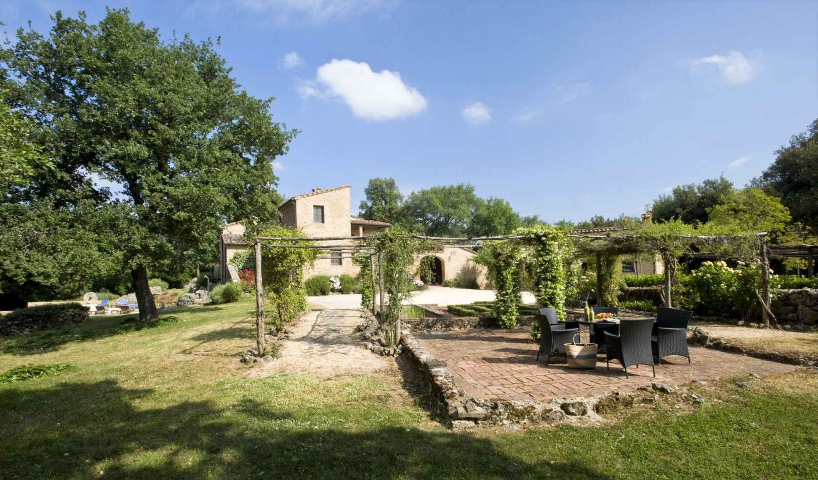 Garden with dining terrace, arbours and view of villa at La Gavelli in Tuscany, Italy