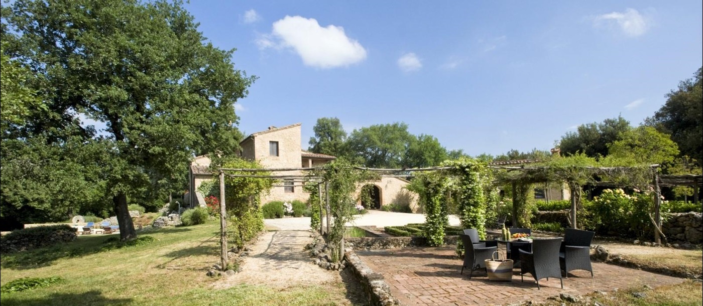 Garden with dining terrace, arbours and view of villa at La Gavelli in Tuscany, Italy