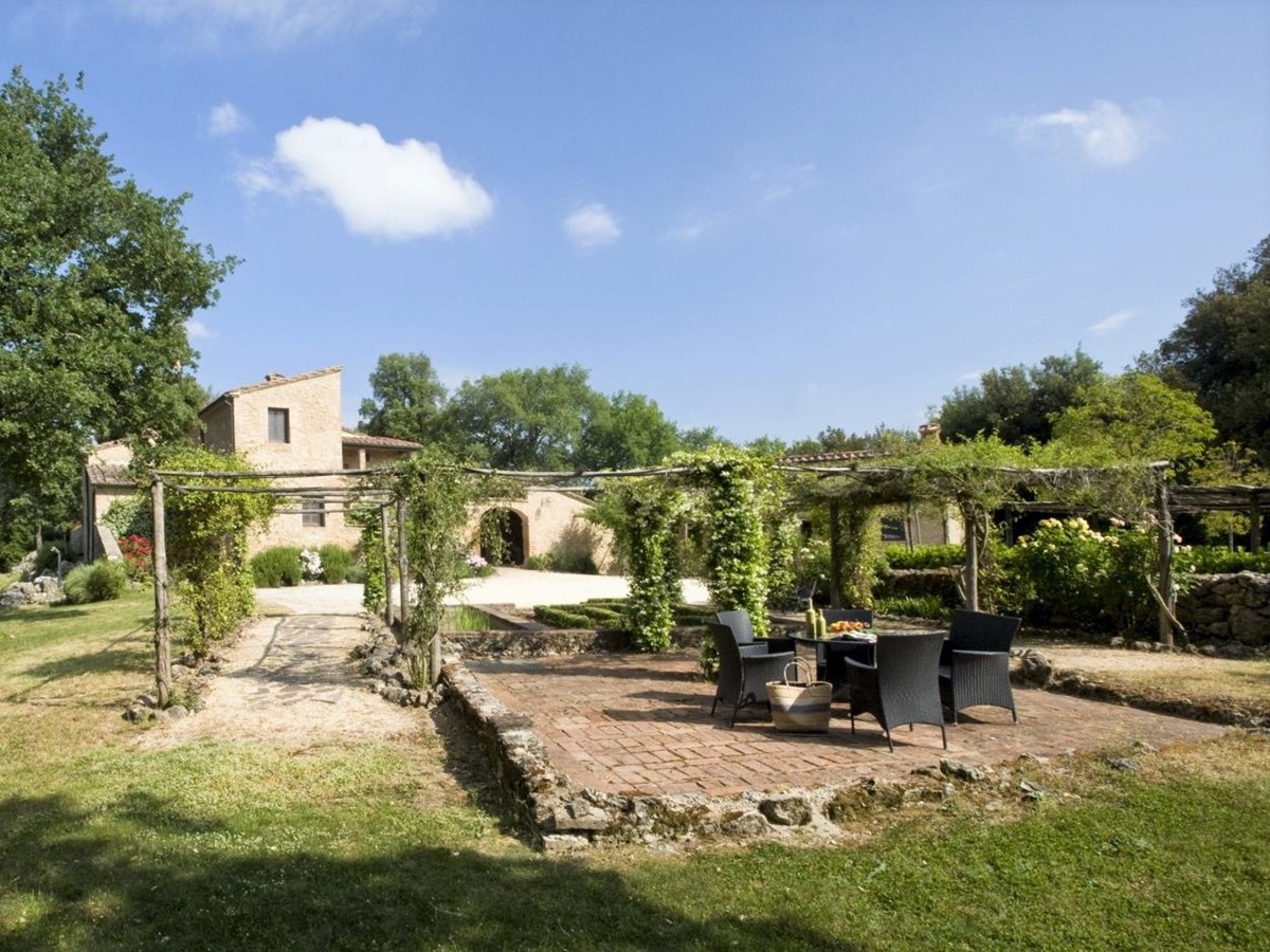 Garden with dining terrace, arbours and view of villa at La Gavelli in Tuscany, Italy