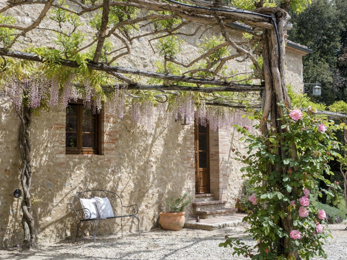 Exterior of villa with arbours, flowers, plants and bench at La Gavelli in Tuscany, Italy