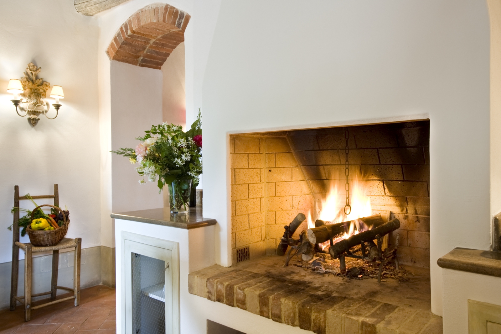 Fireplace and flowers in kitchen at La Gavelli in Tuscany, Italy