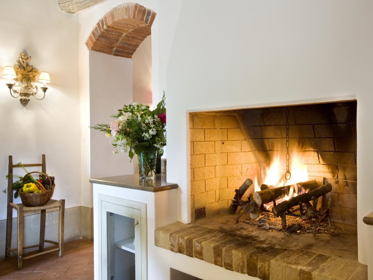 Fireplace and flowers in kitchen at La Gavelli in Tuscany, Italy