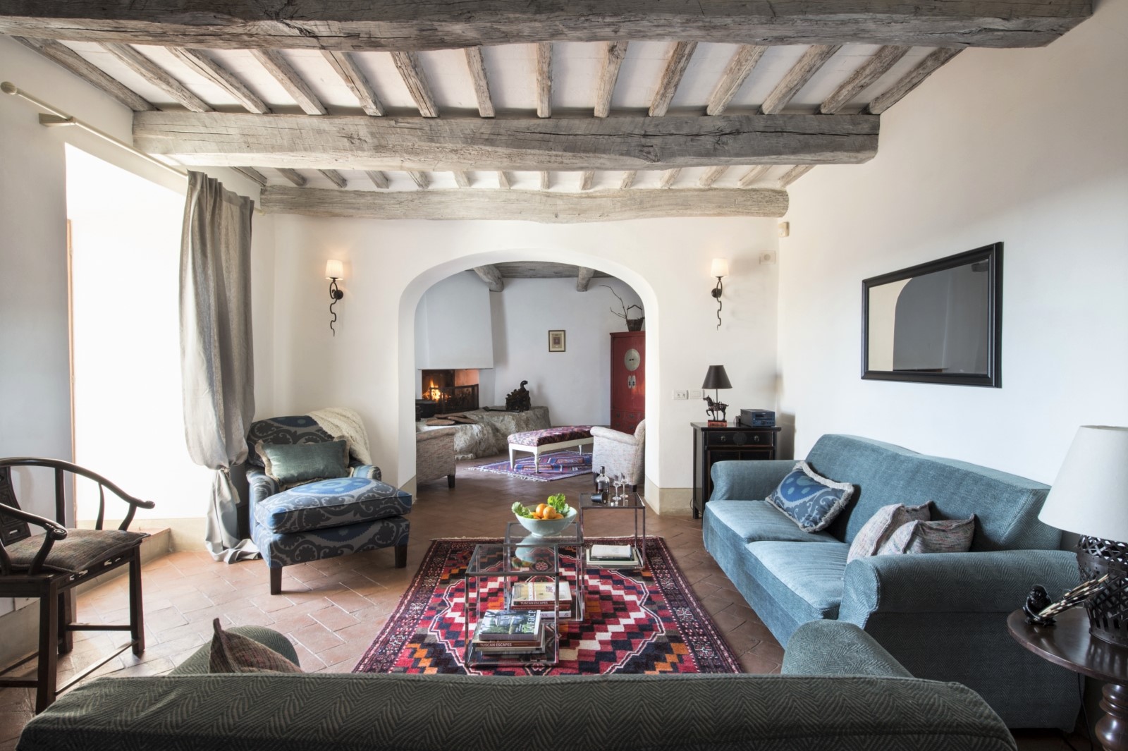 Living room with sofas, armchair, tables & fireplace at La Gavelli in Tuscany, Italy