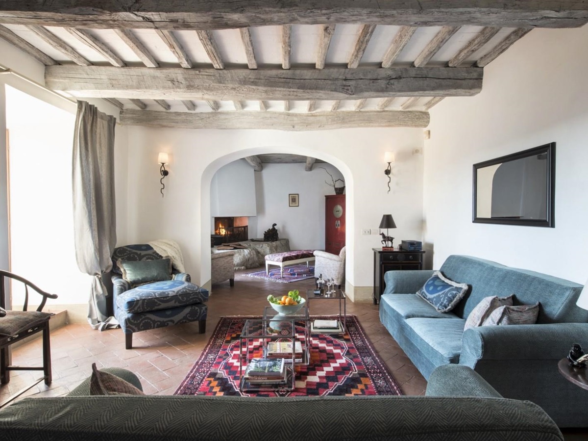 Living room with sofas, armchair, tables & fireplace at La Gavelli in Tuscany, Italy