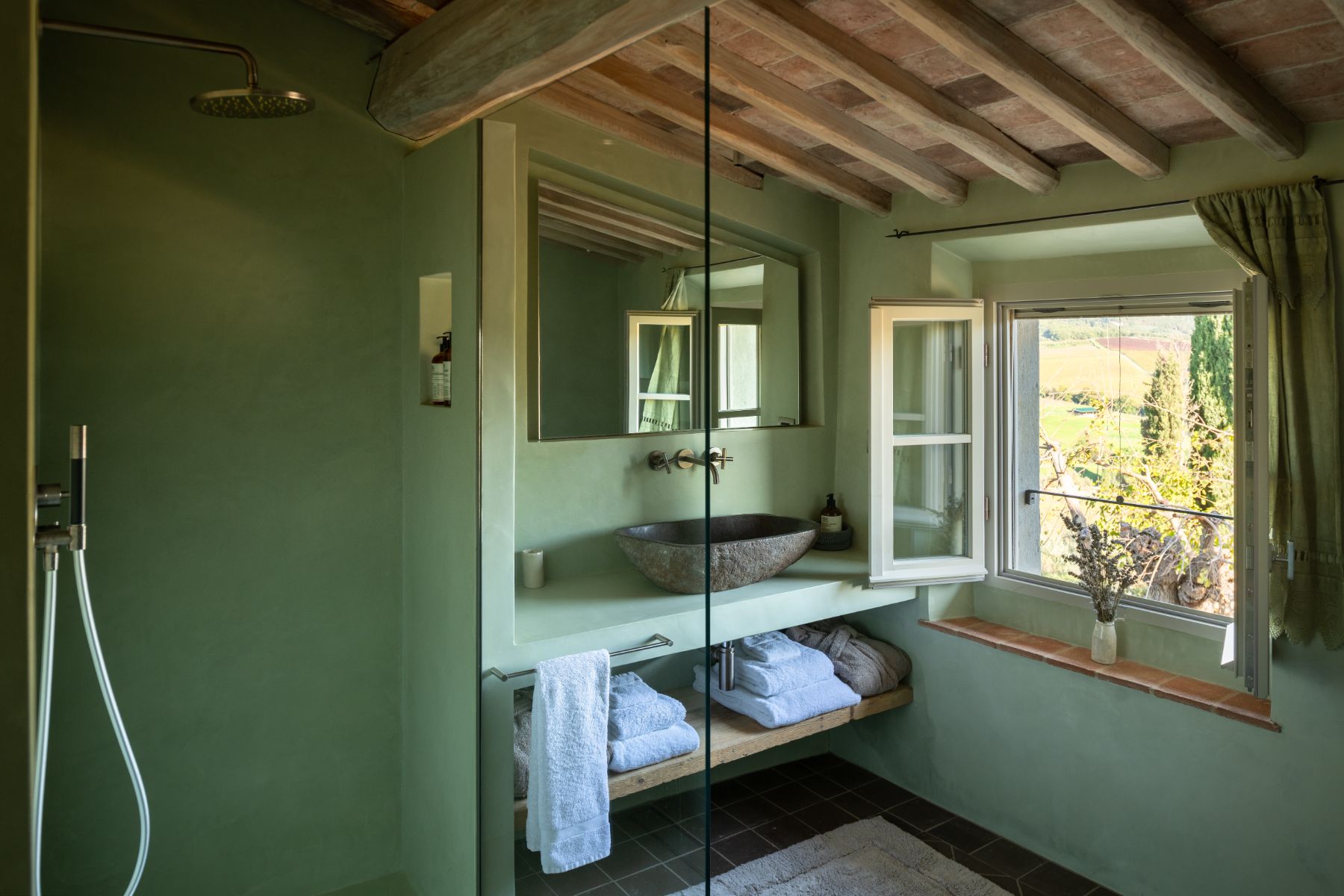 Green bathroom with a shower and washbasin area with large open window at La Regina in Tuscany