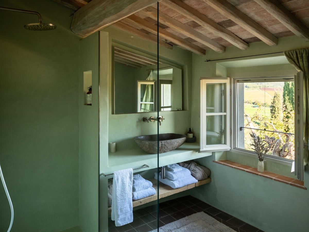 Green bathroom with a shower and washbasin area with large open window at La Regina in Tuscany