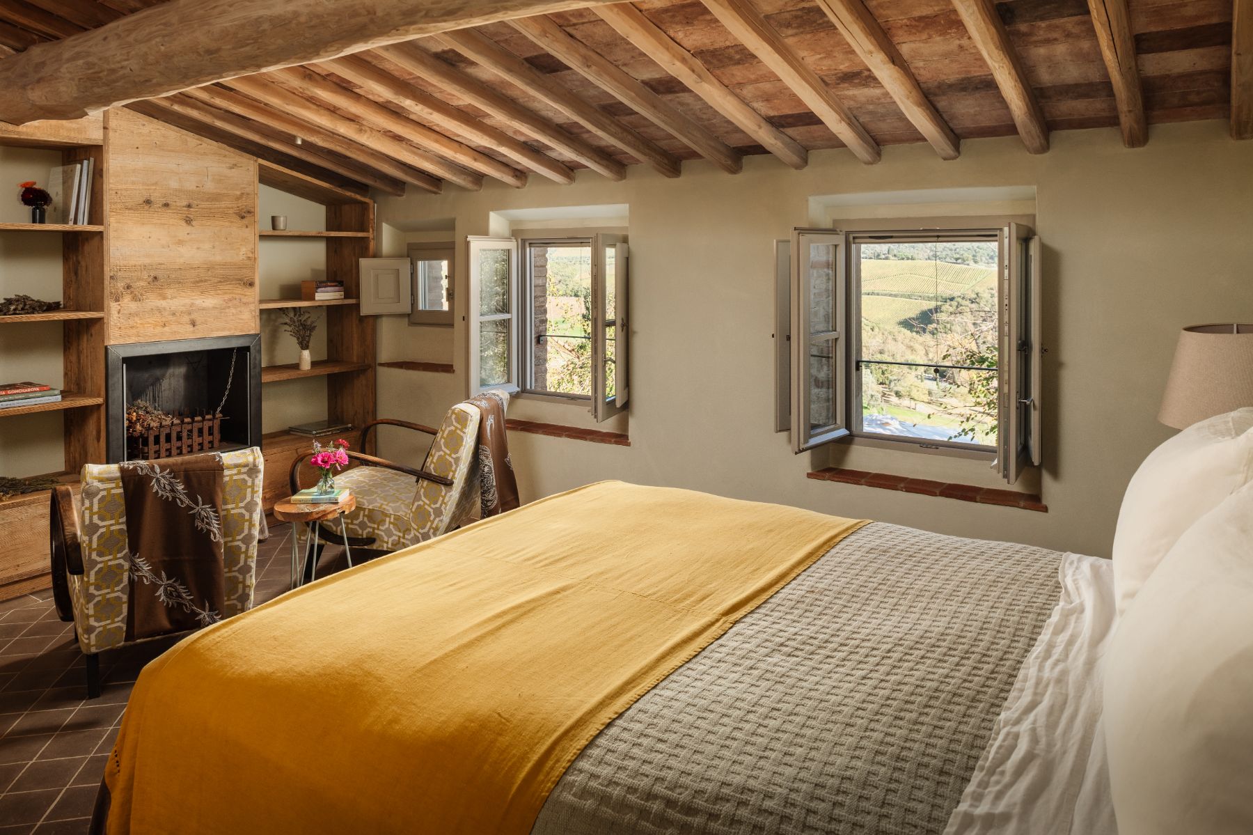 Bedroom with a double bed and a fireplace and armchairs at La Regina in Tuscany