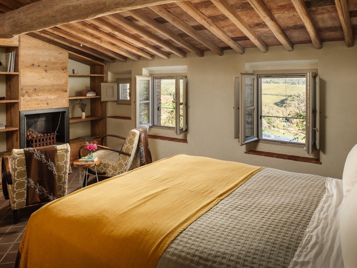 Bedroom with a double bed and a fireplace and armchairs at La Regina in Tuscany