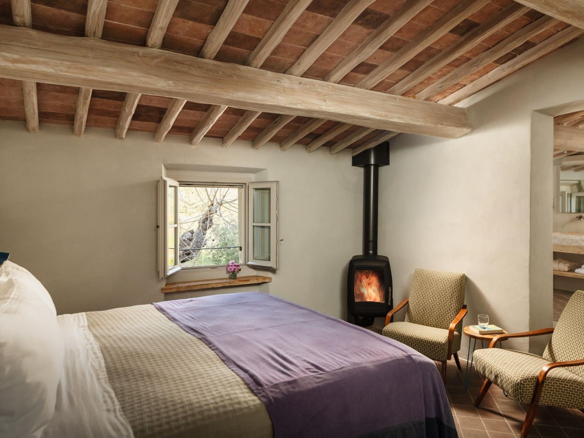 Bedroom with a double bed and small fireplace at La Regina in Tuscany