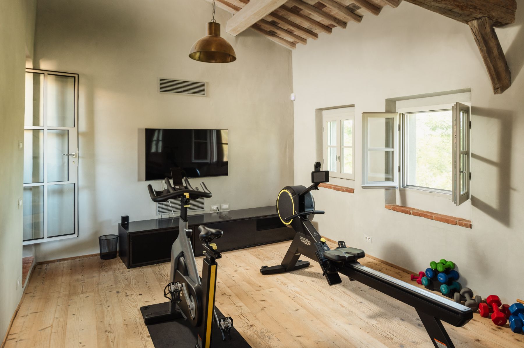 Gym room with gym equipment and a TV on the wall at La Regina in Tuscany