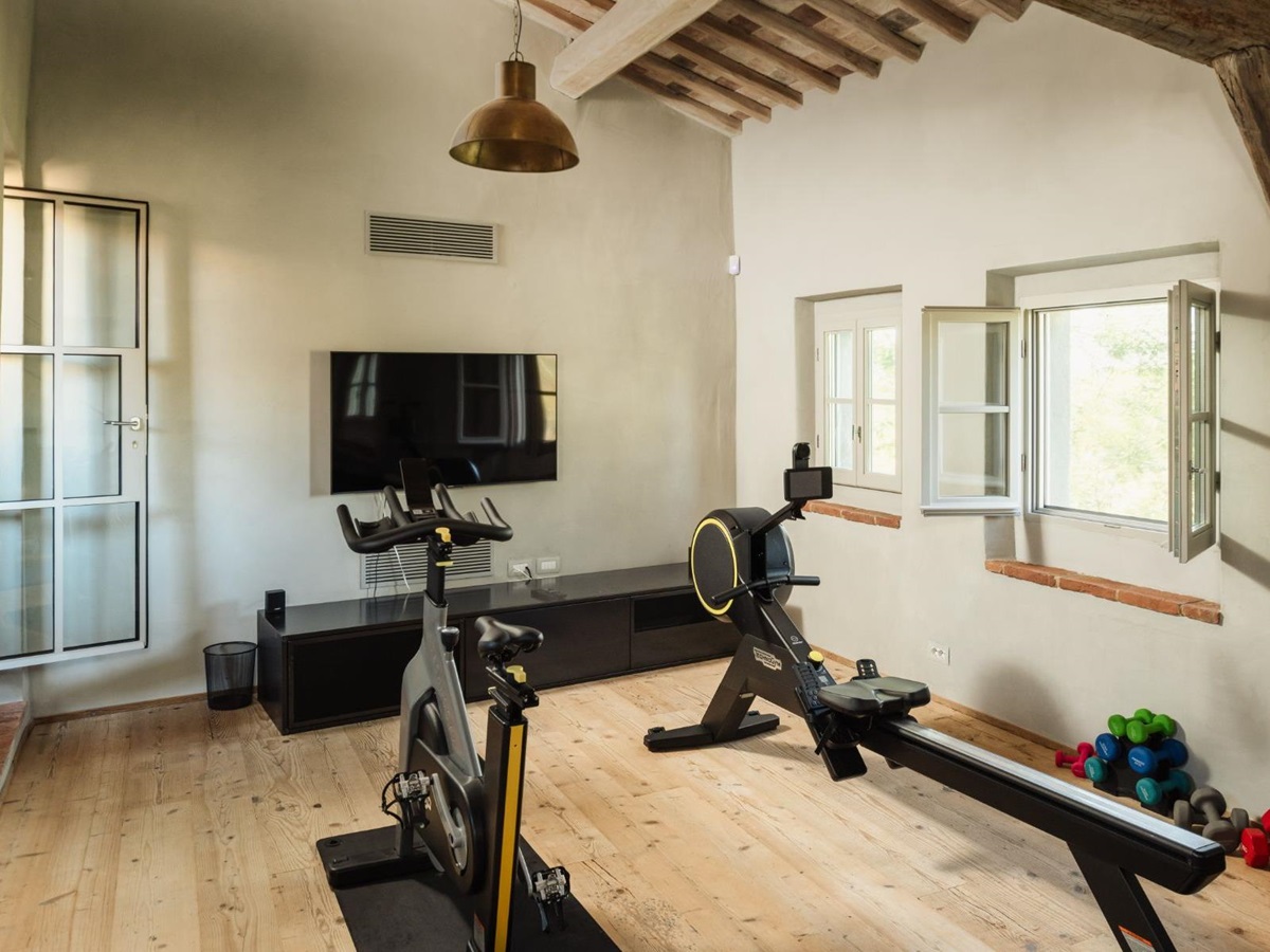Gym room with gym equipment and a TV on the wall at La Regina in Tuscany