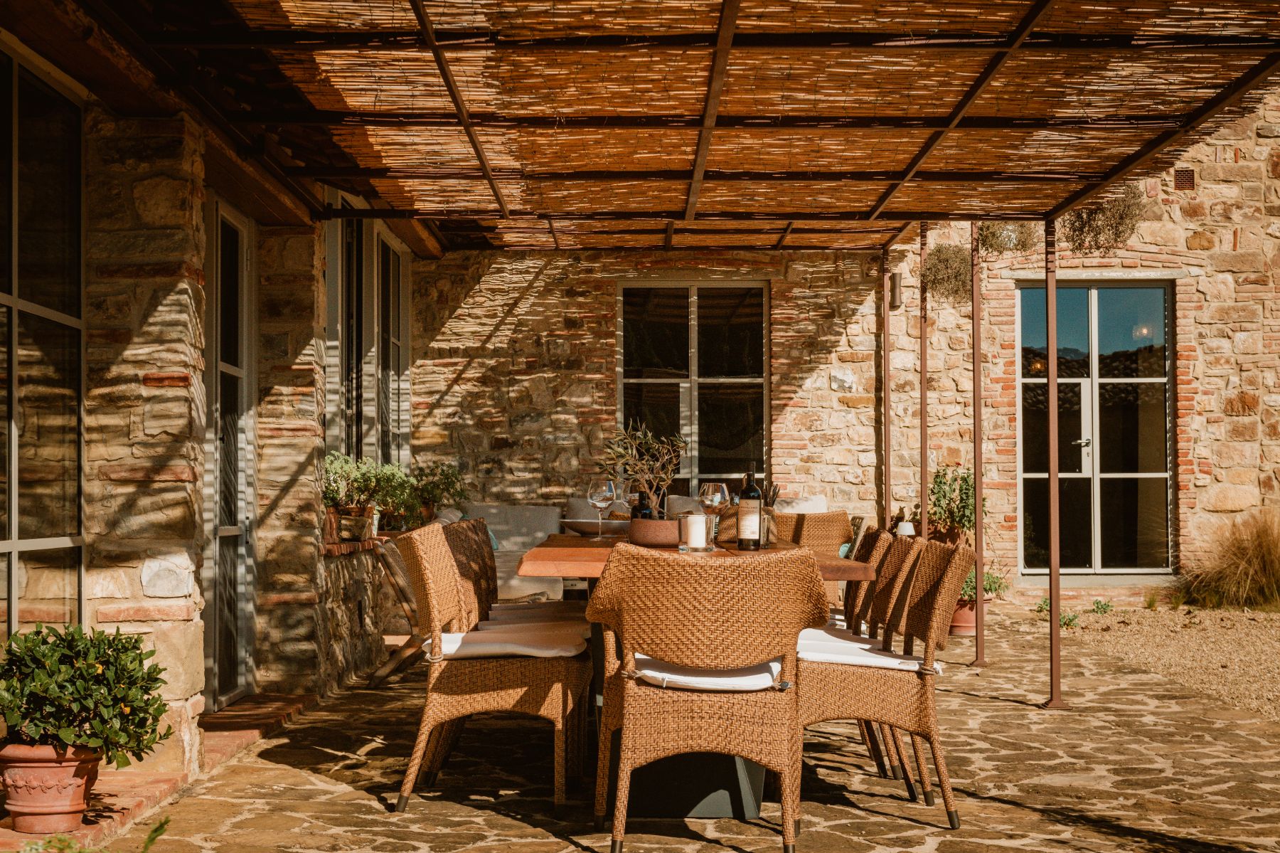 Long outdoor dining table under a wicker roof at La Regina in Tuscany