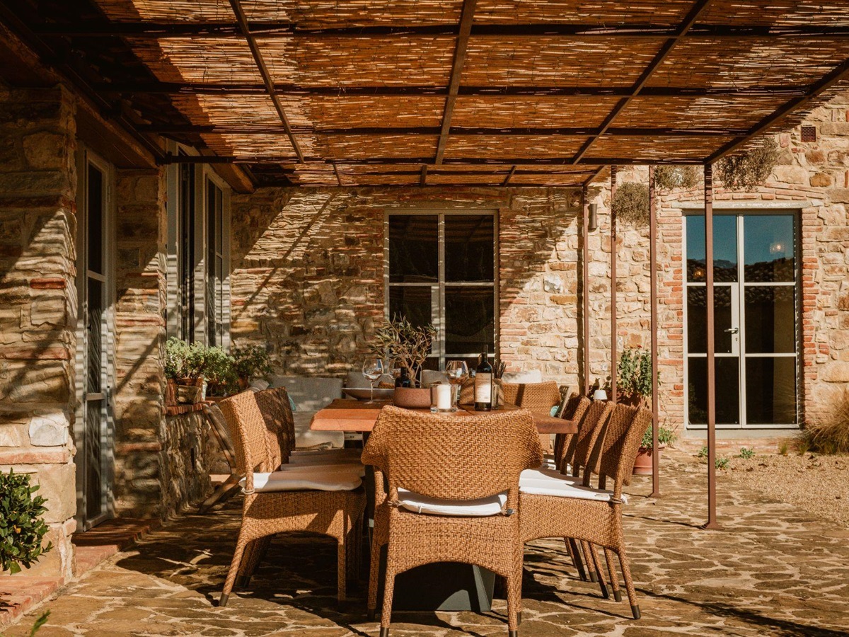 Long outdoor dining table under a wicker roof at La Regina in Tuscany