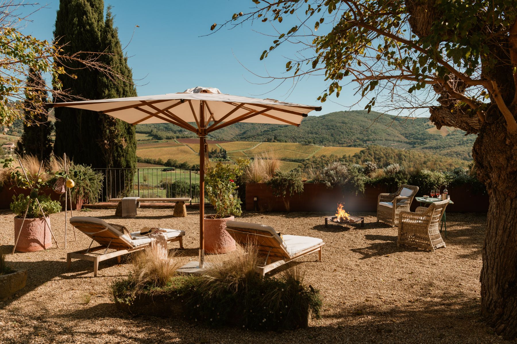 Outdoor fireplace with sun loungers at La Regina in Tuscany