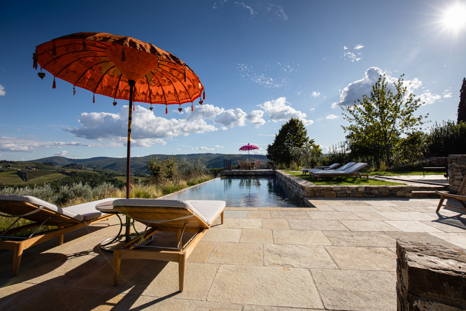 Pool and pool area with sun loungers, umbrellas and countryside view at La Regina in Tuscany, Italy