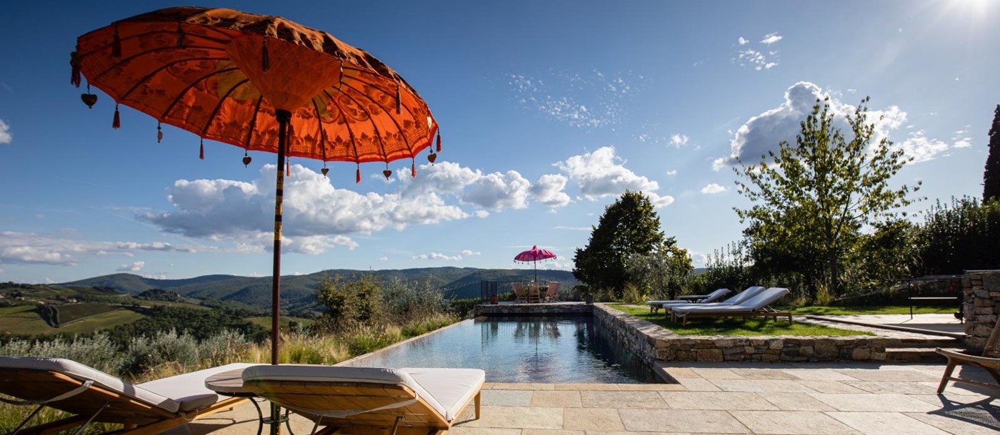 Pool and pool area with sun loungers, umbrellas and countryside view at La Regina in Tuscany, Italy