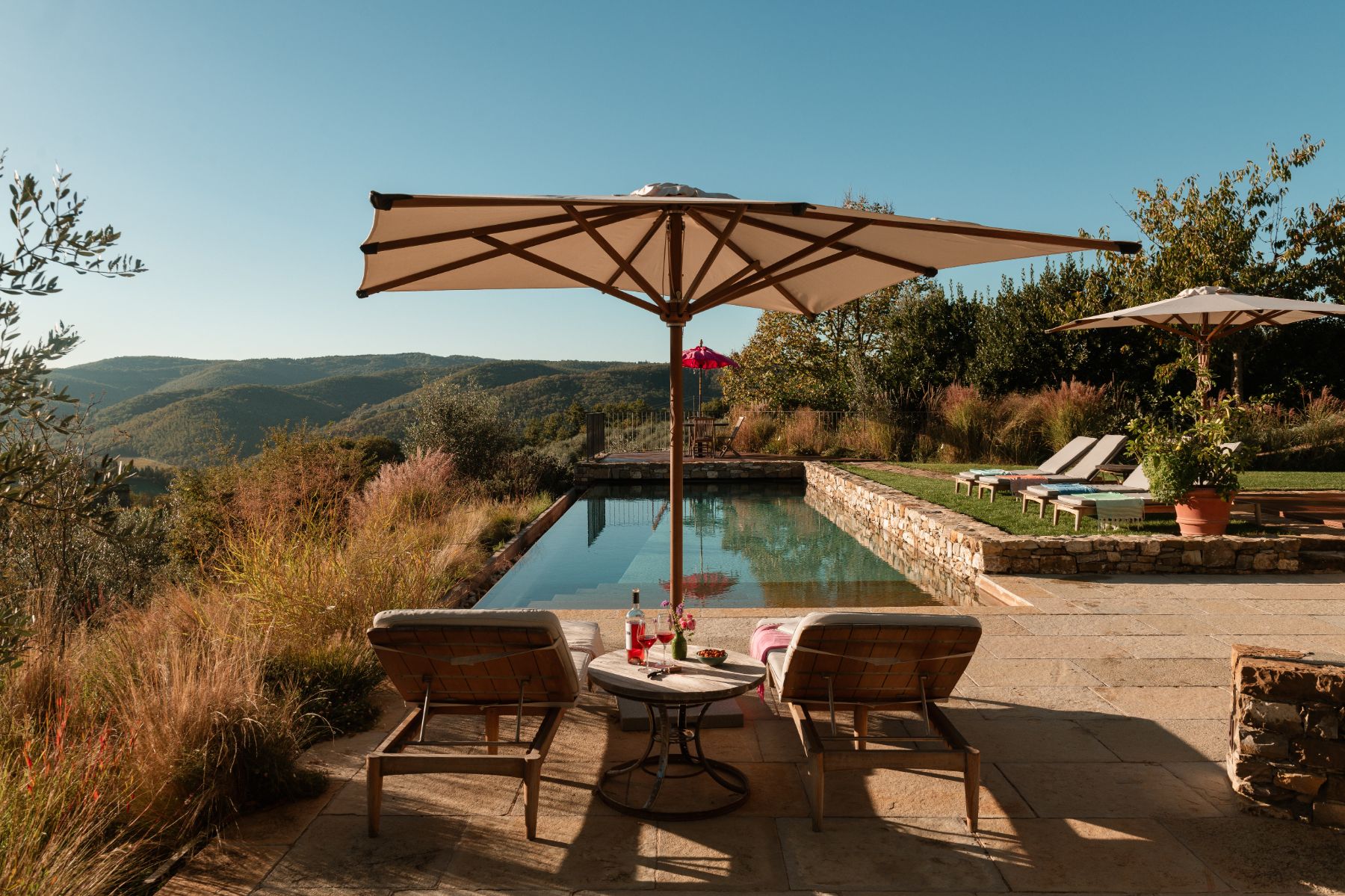 Pool area with sun loungers and parasols at La Regina in Tuscany