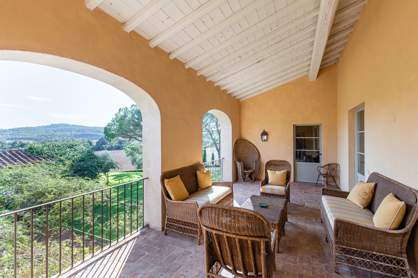 Balcony with comfy chairs, coffee table, stone archways and countryside view at La Vigna in Tuscany, Italy