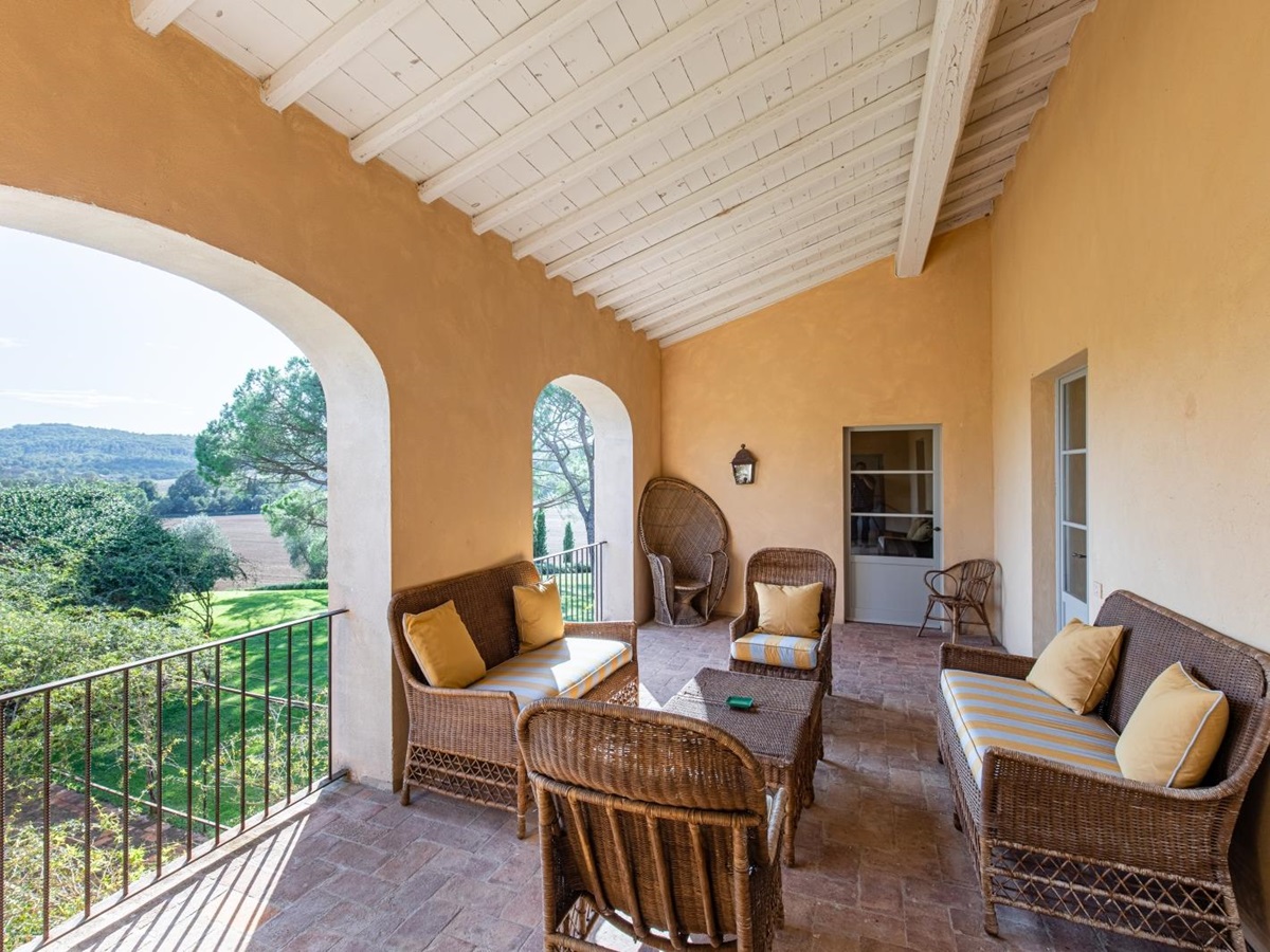 Balcony with comfy chairs, coffee table, stone archways and countryside view at La Vigna in Tuscany, Italy