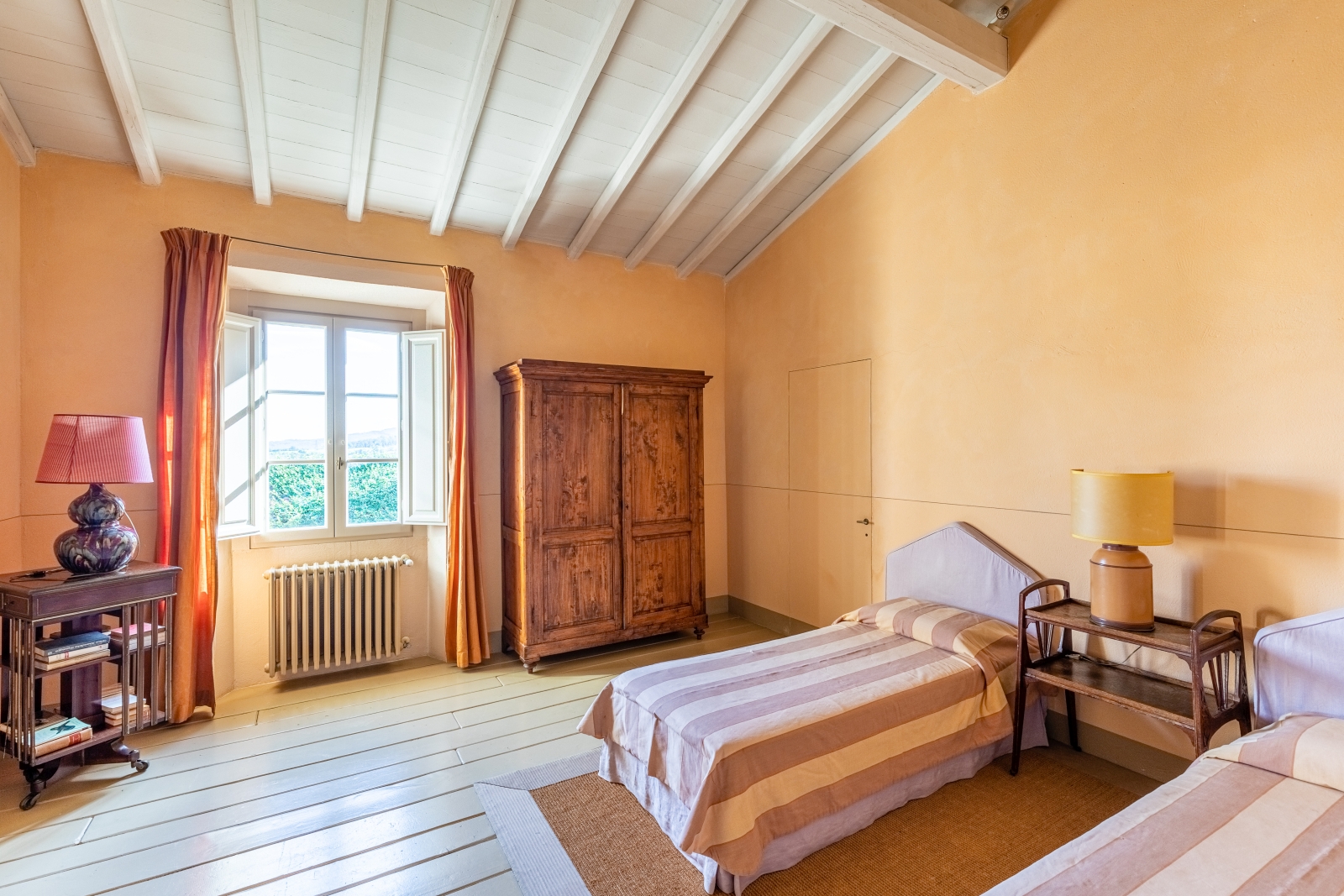 Bedroom with twin beds, bedside table, lamp, wardrobe, window and small table at La Vigna in Tuscany, Italy
