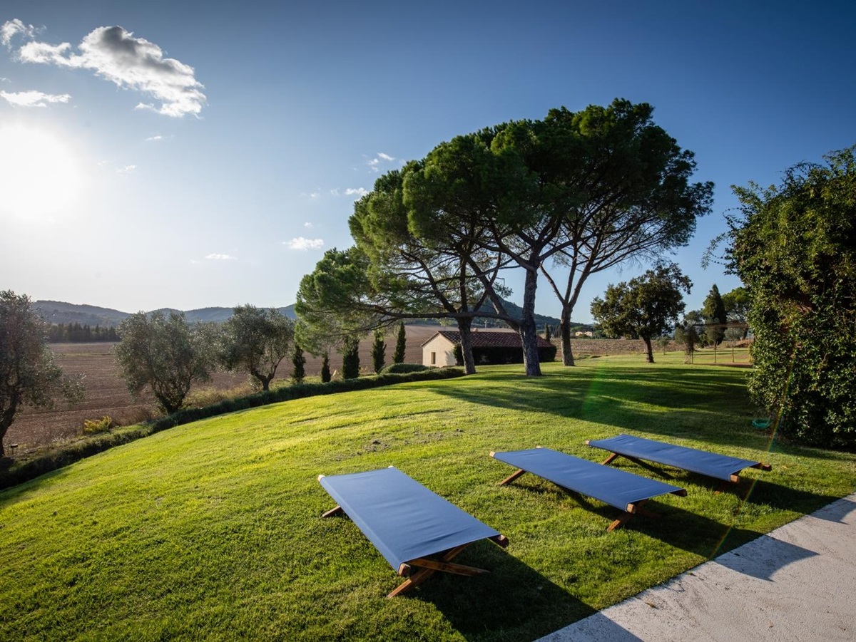 Garden with sun loungers, trees, countryside view and guest house at La Vigna in Tuscany, Italy