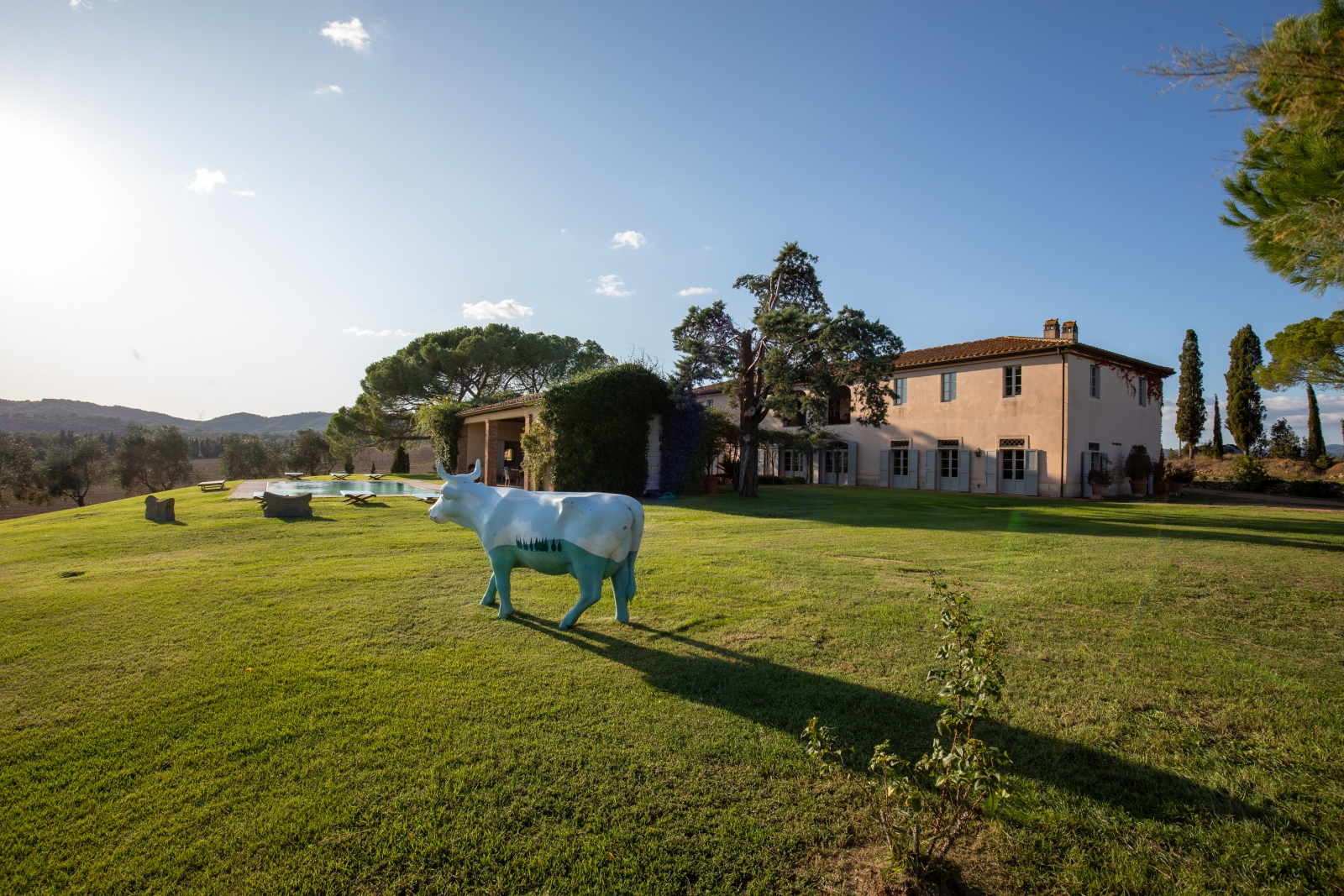 Garden with cow statue, pool, outdoor dining area and trees at La Vigna in Tuscany, Italy