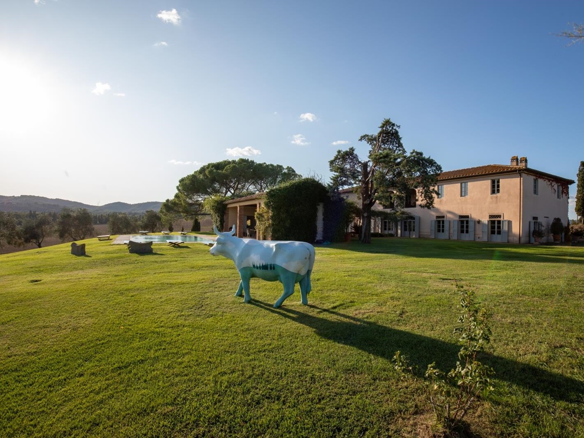 Garden with cow statue, pool, outdoor dining area and trees at La Vigna in Tuscany, Italy