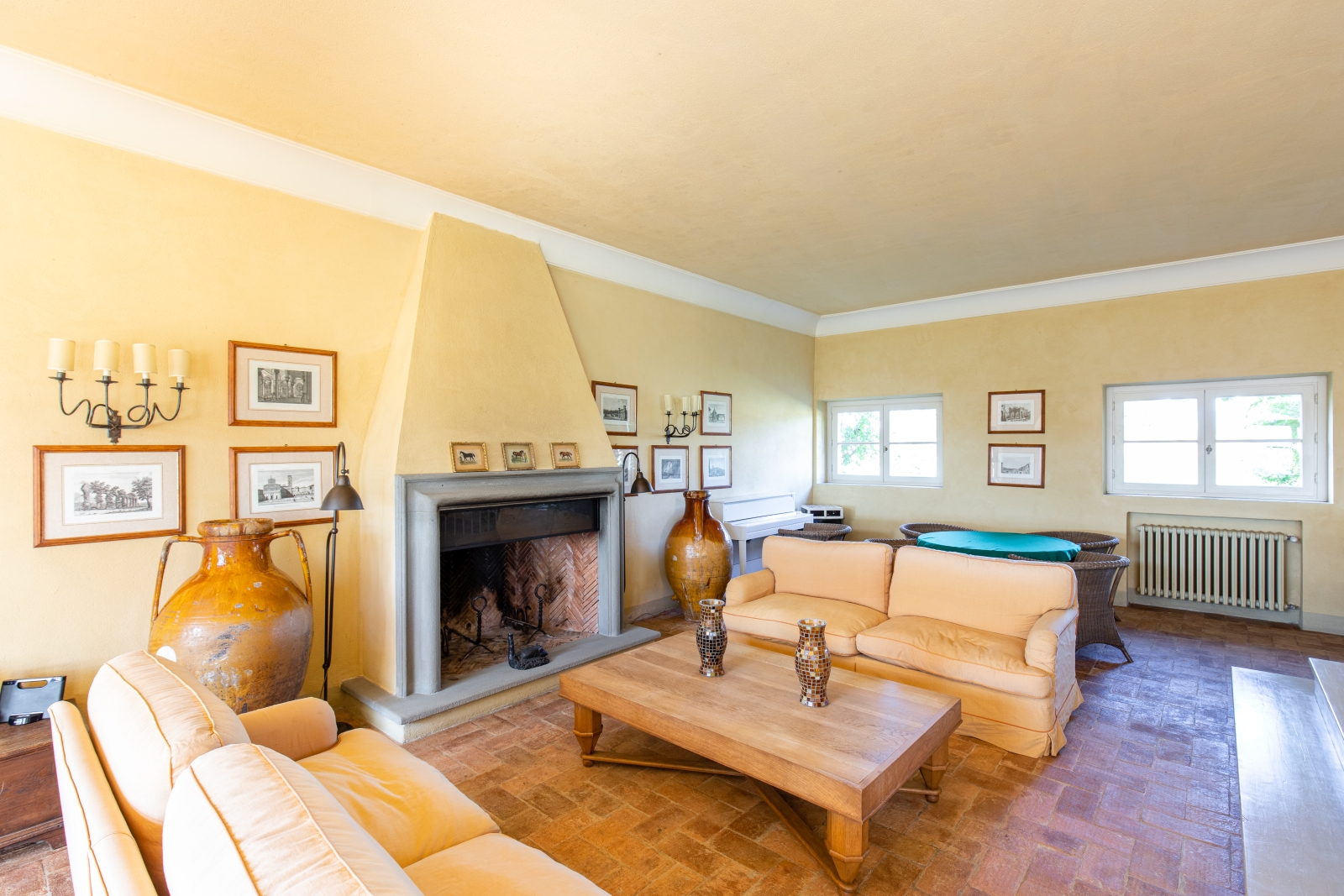 Living room with sofas, coffee table, dining table, chairs, fireplace, picture frames & candles at La Vigna in Tuscany, Italy