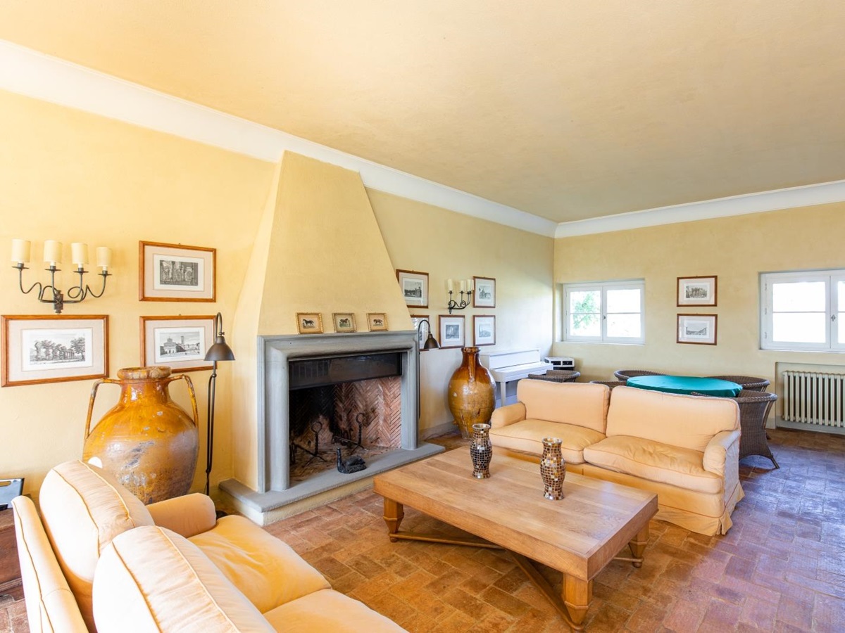Living room with sofas, coffee table, dining table, chairs, fireplace, picture frames & candles at La Vigna in Tuscany, Italy