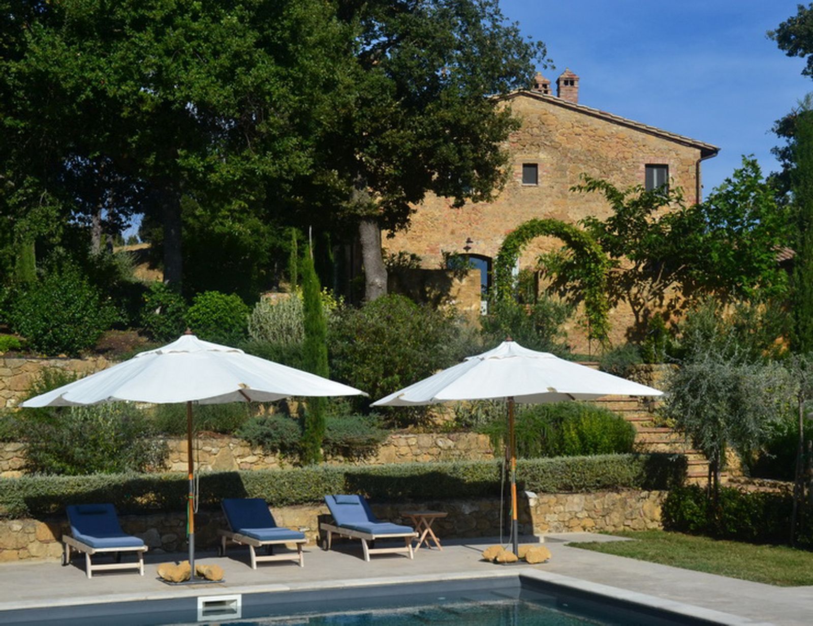 Pool loungers with villa in the background at Podere Caterina in Tuscany