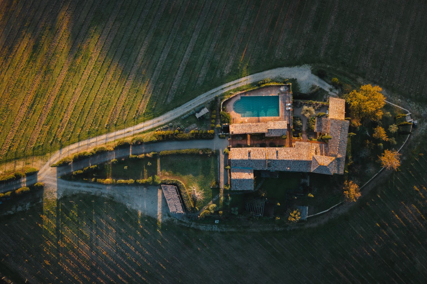 Overhead drone view of Podere Cipressi and the pool area and driveway in Tuscany