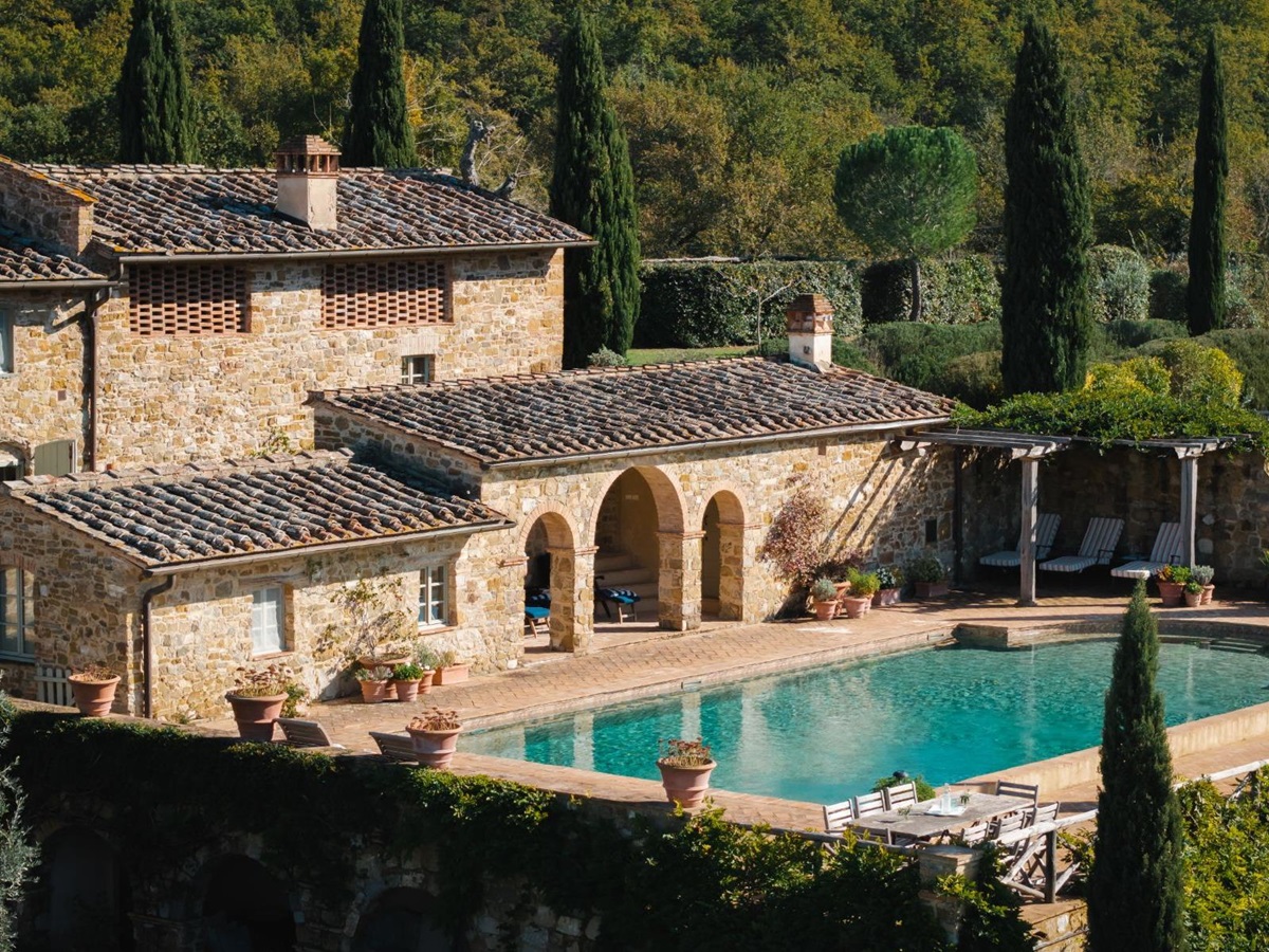 Drone view of the pool area and an outdoor dining table at Podere Cipressi in Tuscany