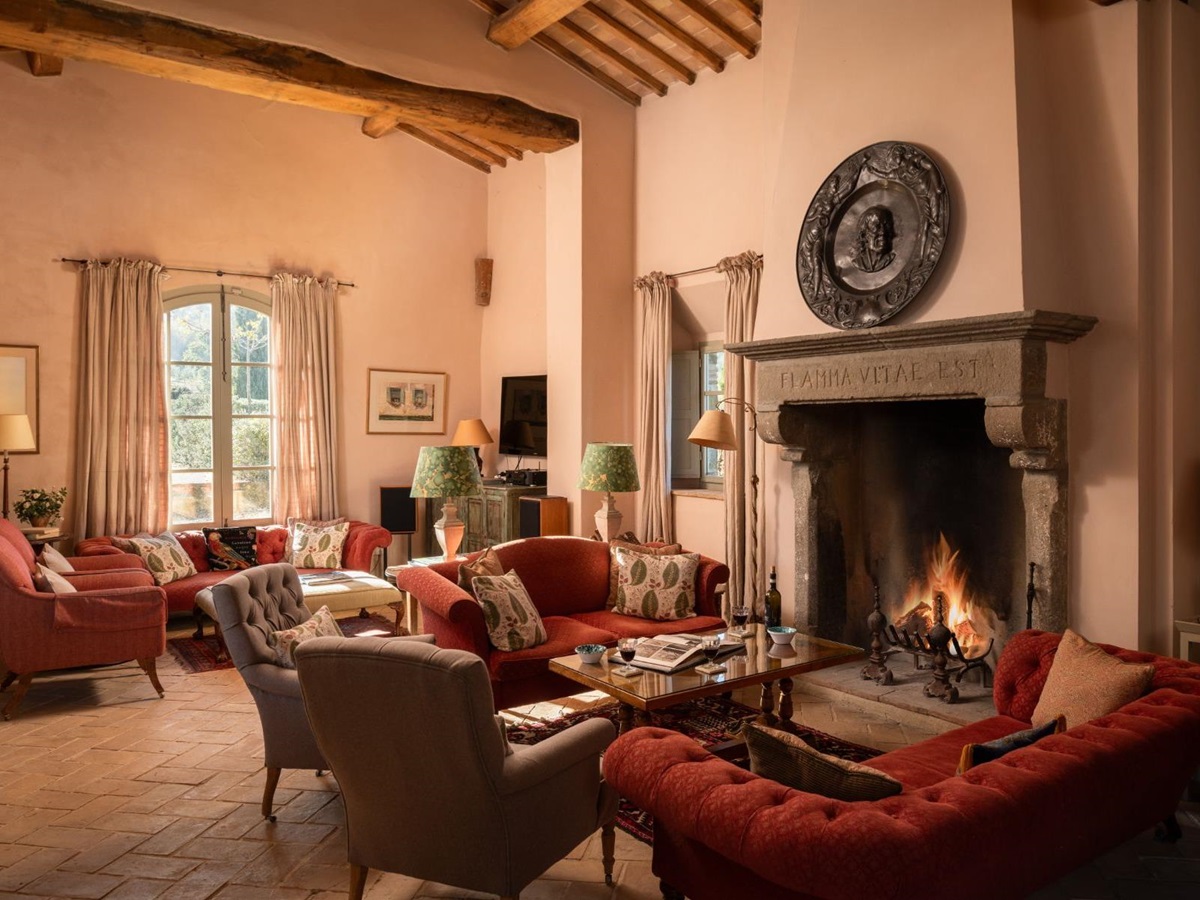 Living room with sofas and a large fireplace at Podere Cipressi in Tuscany