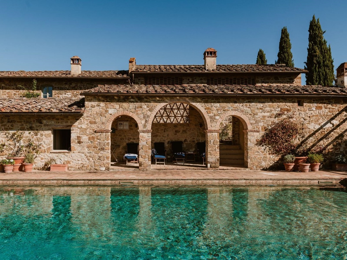 View of the outdoor swimming pool with sun loungers at Podere Cipressi in Tuscany
