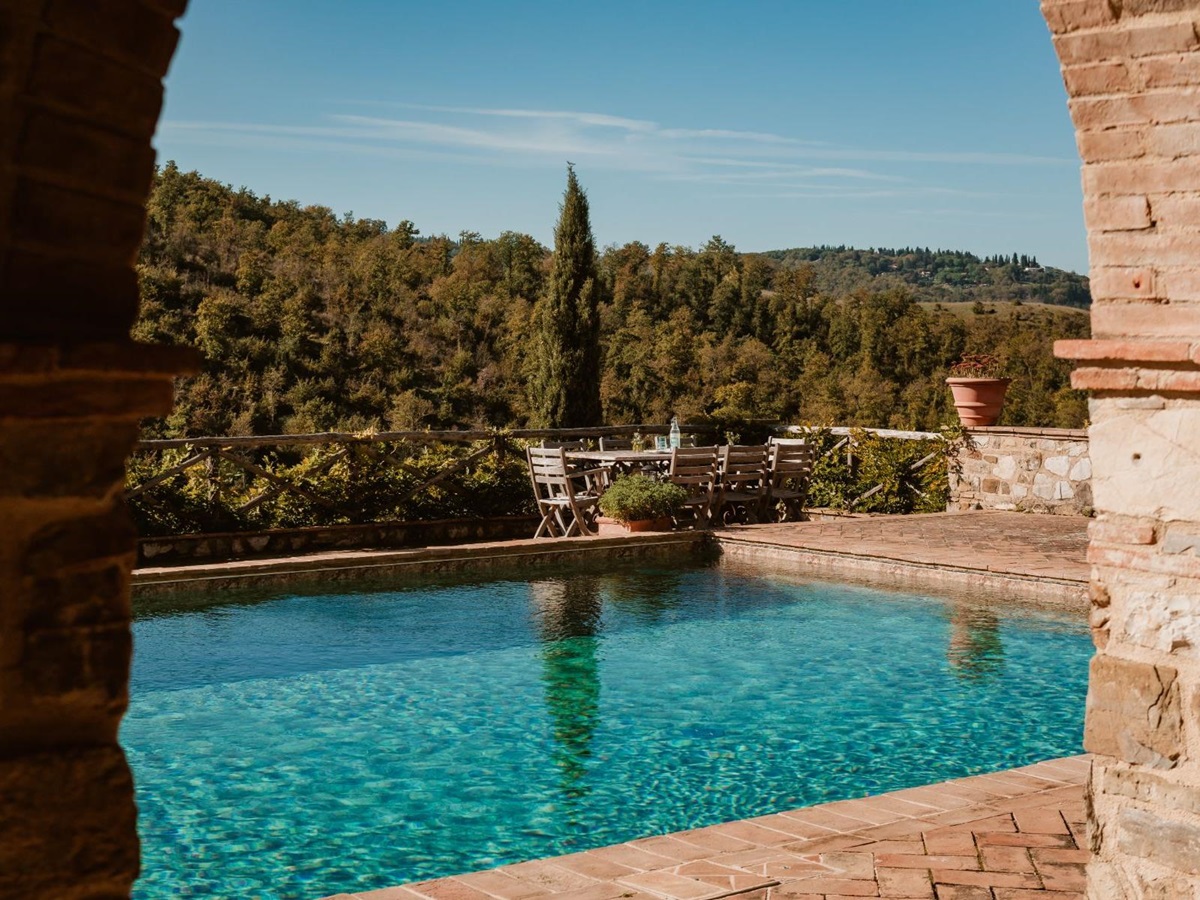 Outdoor swimming pool with view of the outdoor dining table at Podere Cipressi in Tuscany
