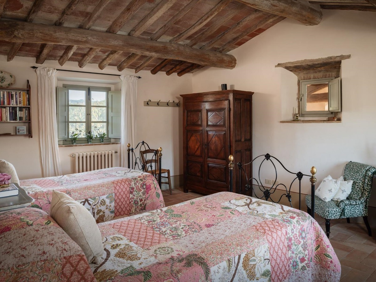 Twin room with a wooden wardrobe and armchair at Podere Cipressi in Tuscany