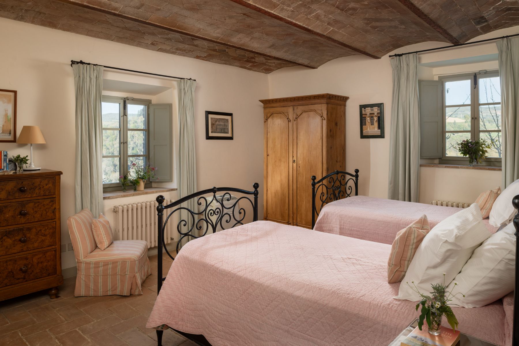 Twin bedroom with pink bedding and a wooden wardrobe at Podere Cipressi in Tuscany