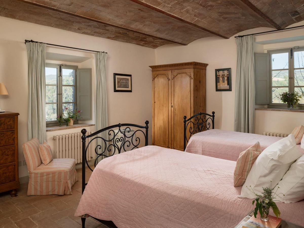 Twin bedroom with pink bedding and a wooden wardrobe at Podere Cipressi in Tuscany