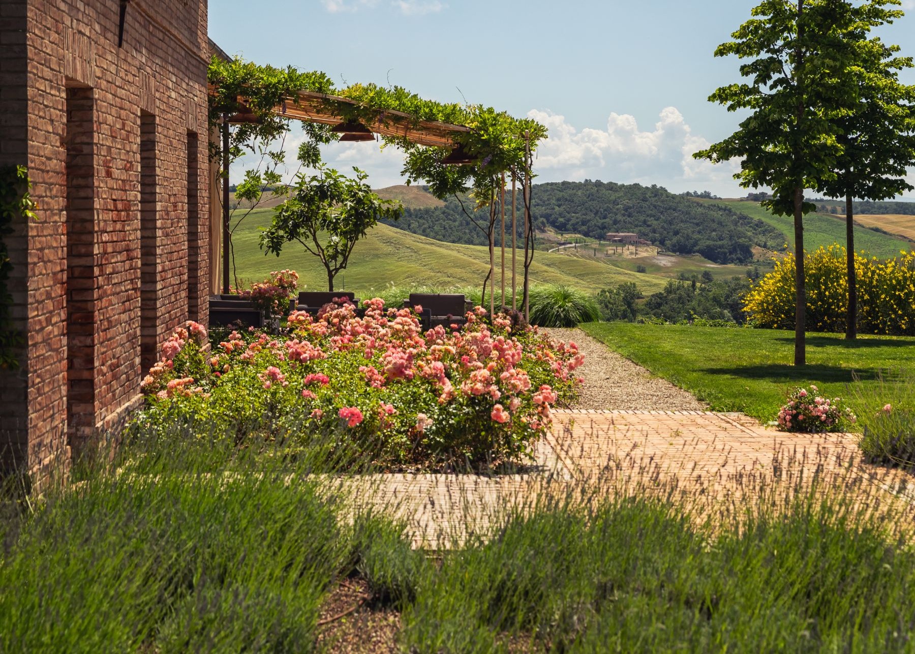 Outdoor seating with pergola and pretty flower beds at the front of Podere Martino, a luxury villa in Tuscany