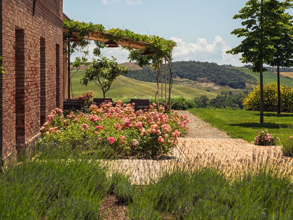 Outdoor seating with pergola and pretty flower beds at the front of Podere Martino, a luxury villa in Tuscany