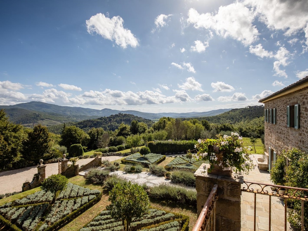 View of patio, front garden, flowers, driveway and mountains from balcony at Tenuta Cantata in Tuscany, Italy
