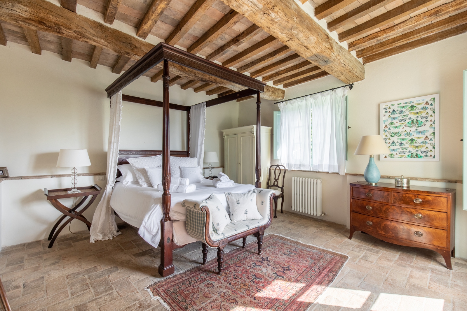 Bedroom with four poster bed, bedside table, lamps, sofa, chest of drawers and wardrobe at Tenuta Cantata in Tuscany, Italy