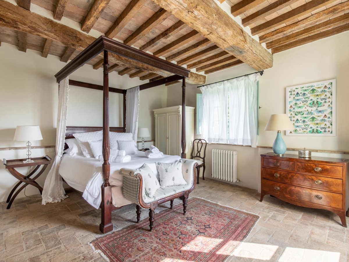 Bedroom with four poster bed, bedside table, lamps, sofa, chest of drawers and wardrobe at Tenuta Cantata in Tuscany, Italy