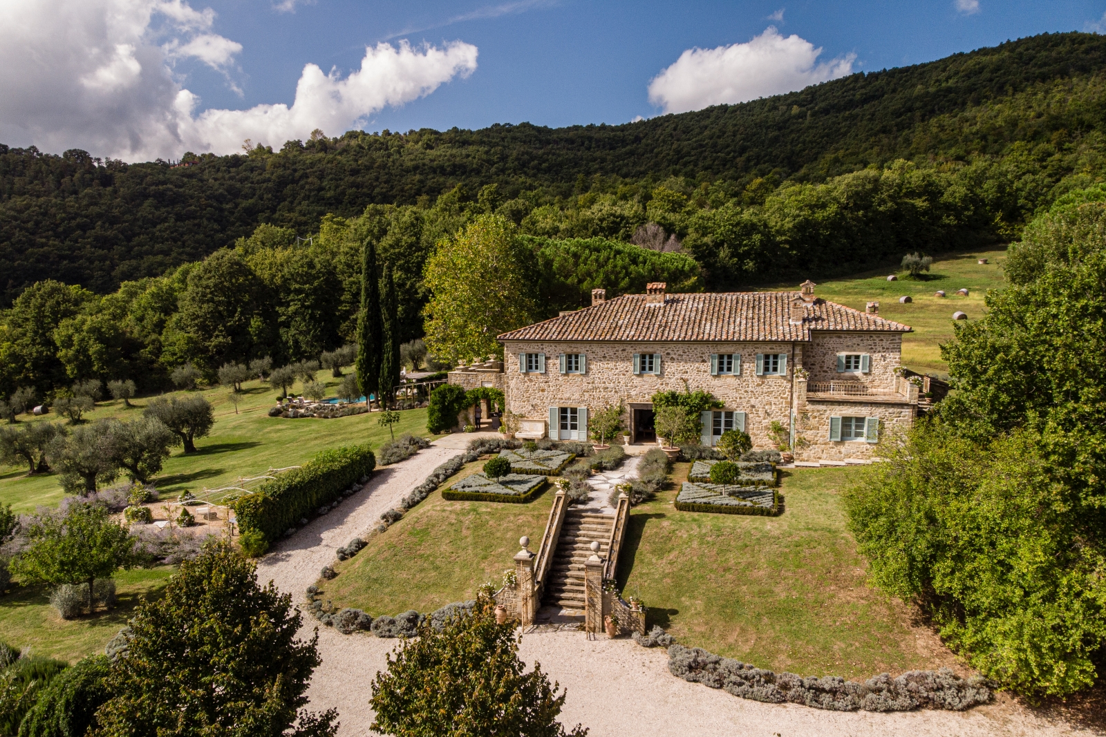 Aerial view of villa with gardens, trees, forest, flowers, pool, patio and driveway at Tenuta Cantata in Tuscany, Italy
