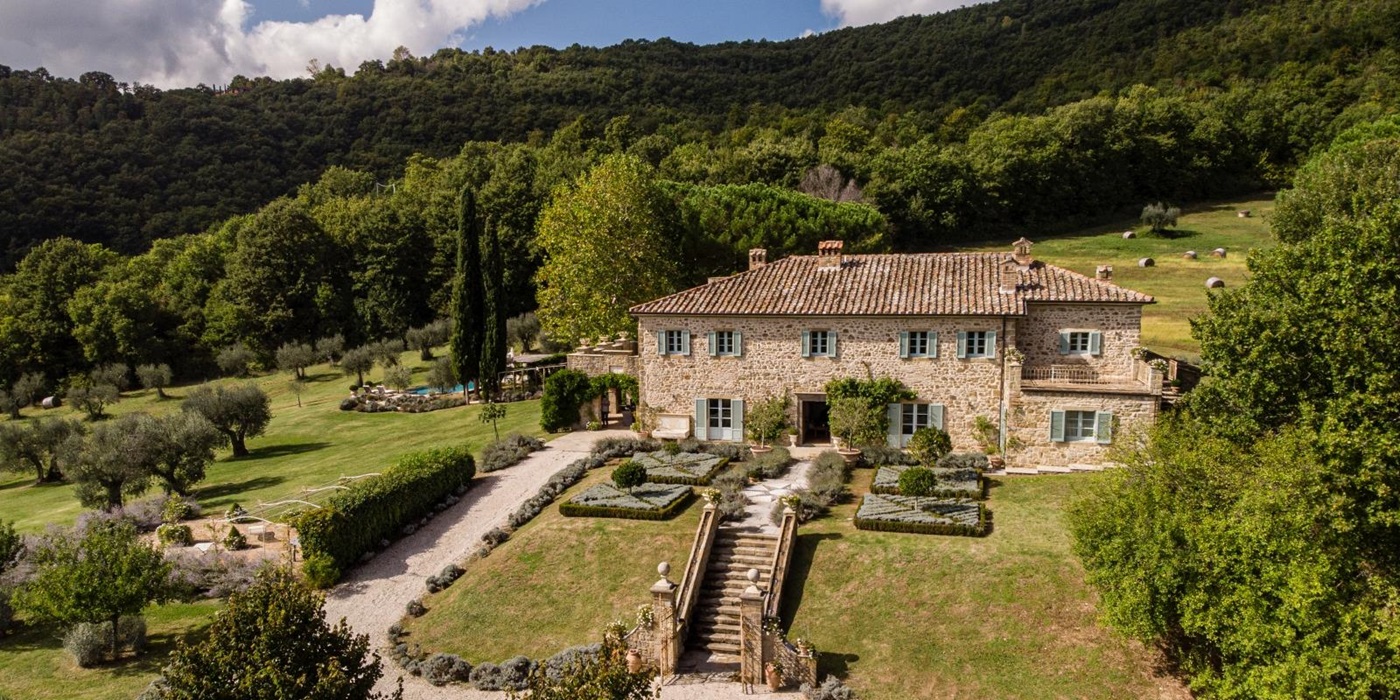 Aerial view of villa with gardens, trees, forest, flowers, pool, patio and driveway at Tenuta Cantata in Tuscany, Italy